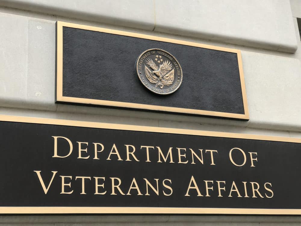 A sign of The Department of Veterans Affairs hangs outside of an official military building.