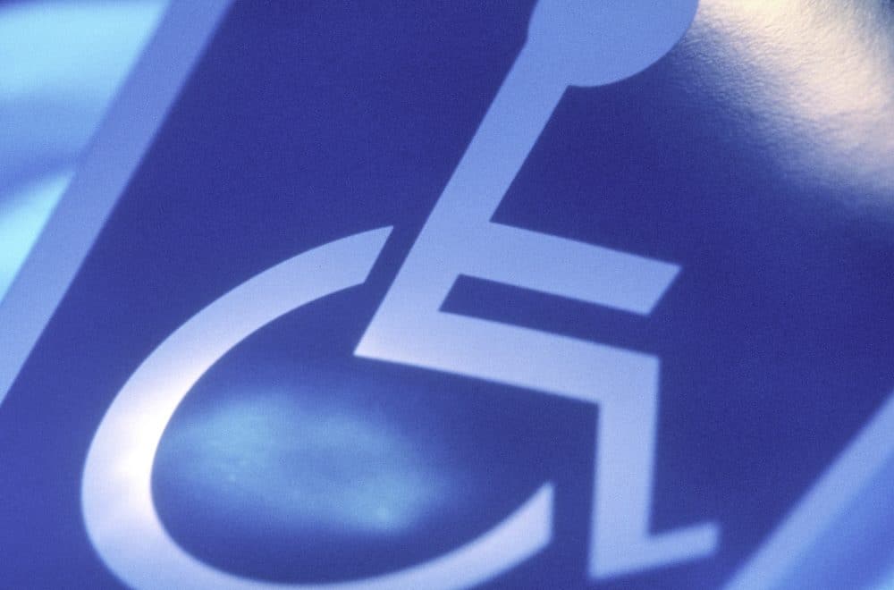 A handi-capped sign glows blue against a wall.